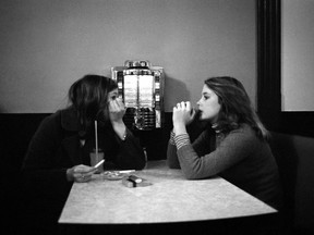 Sisters Patty, left, and Kelly whisper to each other in a restaurant filled with teenagers in Dollard-des-Ormeaux in November 1976.