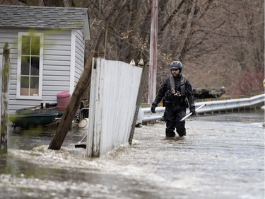 A Montreal police officer checks on homes as the Rivière des Prairies rises, flooding Île-Mercier in Montreal on Wednesday May 3, 2017.