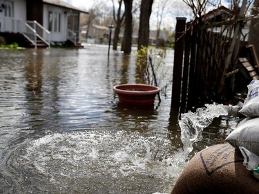 A pump hose sends water back into the river as the Rivière des Prairies rises, flooding Île-Mercier in Montreal on Wednesday May 3, 2017.