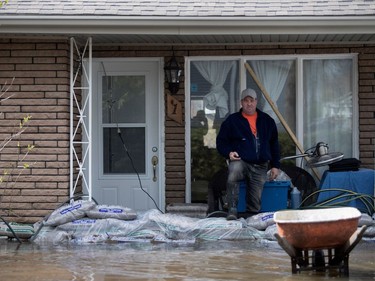 A volunteer keeps his eye on the water levels after a group of neighbours pitched in to build sand walls around homes affected by the Rivière des Prairies rising and flooding Île-Mercier in Montreal on Wednesday May 3, 2017.