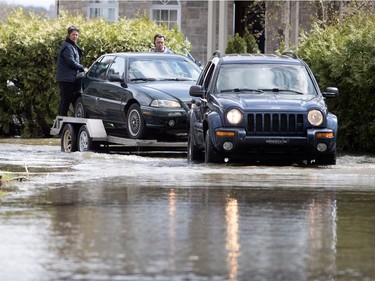 Rolland Bouvier helps neighbours Mylène Nadon, left, and Jocelyn Bouchard shuttle their cars to safety as the Rivière des Prairies rises flooding Île-Mercier in Montreal on Wednesday May 3, 2017.