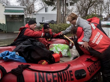 Montreal fire department help a woman off Île Mercier as flooding continues on Île Mercier, off Île Bizard on Friday, May 5, 2017.  (Dave Sidaway / MONTREAL GAZETTE)