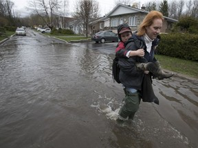 Dominique Palardy carries her son Zachary towards their flooded house on Joly street in Ile Bizard on Saturday May 6, 2017. (Pierre Obendrauf / MONTREAL GAZETTE)