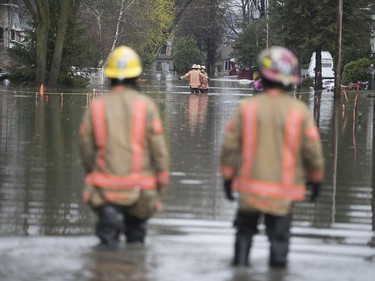 Montreal firefighters make their way on flooded Jean-Yves St. in Ile Bizard on Saturday May 6, 2017.