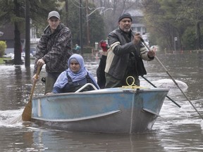 Tauseef Bhatti, front, and wife Weena Sehar make their way to their flooded house on Jean-Yves St. in Île-Bizard on May 6, 2017.