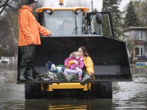 Two-year-old Olivia Kulisz and her mother Stephanie are evacuated in the bucket of a loader from rue Jean-Yeves in Île Bizard on Saturday May 6, 2017.