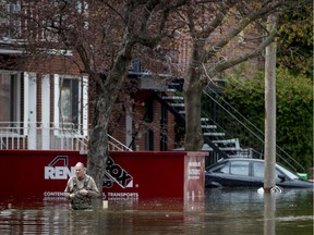 A resident of Cousineau St. in the Ahuntsic-Cartierville borough of Montreal makes his way to higher ground on Sunday, May 7, 2017.