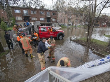 Firefighters and city employees sandbag the front lawn of a home on Cousineau St. in the Cartierville Ahuntsic borough of Montreal May 7, 2017.