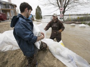 Louis-Philippe Martin, left, brings bags to Mathieu Audetteas they shore up Saint-Martin street triplex in Pierrefonds  on Sunday May 7, 2017.