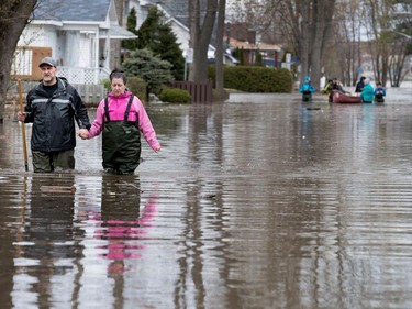 Robert Balic and Brigitte Côté's walk carefully out of the flood zone in Laval West as water levels continue to rise  in Montreal on Sunday, May 7, 2017.