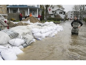 Valerie Turcotte (right) looks at the sandbags surrounding her St-Martin street triplex in Pierrefonds on May 7.