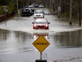 A motorist braves the deep water that has formed in a dip in Main Rd. in Hudson, west of Montreal May 8, 2017.