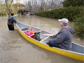 Rachel Dow pulls a canoe as she and family friend Pierre Cormier bring a fresh supply of gas for the two trash pumps that are keeping the water level in her parent's home to a few inches, in Hudson, west of Montreal, on Monday May 8, 2017.  (Allen McInnis / MONTREAL GAZETTE)