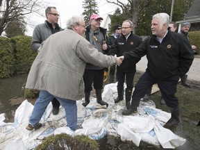 Quebec Premier Philippe Couillard talks to a resident of Des Anges St. in Oka during an impromptu tour of the flooded town on Tuesday May 9, 2017. Couillard is at his best in the aftermath of tragedy, Don Macpherson writes; that's when his usual aloofness gives way to compassion.