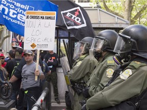 Police officers in riot gear guard the entrance of the National Assembly as striking construction workers demonstrate against back-to-work legislation on May 29.