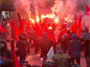 Protesters light flares during a May Day demonstration Monday, May 1, 2017 in Montreal. Anti-capitalists marched through downtown Montreal on Monday to disturb what they claimed were the corporate playgrounds of the scheming rich.