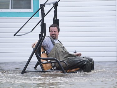 A man sits on a swing chair surrounded by flood water in the town of Rigaud, west of Montreal, Saturday, May 6, 2017, following flooding in the region.