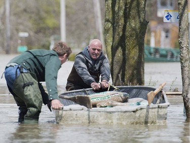 Two men pull a small boat loaded with sandbags in the town of Rigaud, west of Montreal, Saturday, May 6, 2017, following flooding in the region.