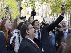 Prime Minister Justin Trudeau stops for selfies as Premier of Quebec Philippe Couillard and Mayor Coderre as look as they walk to the Notre-Dame Basilica to attend a mass marking the 375th anniversary of the founding of Montreal on Wednesday May 17, 2017.