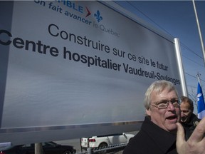 Quebec Health Minister Gaetan Barrette stands in front of a sign announcing a planned new regional hospital in Vaudreuil-Dorion in April 2016.