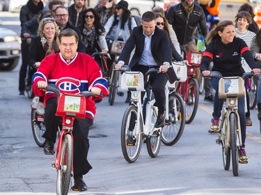 Montreal mayor Denis Coderre, left, rides a Bixi bicycle designed by the City of Montreal as he is followed by many Quebec personalities with their own Bixi designs during an event to mark the first day of the season for the Bixi bike-sharing program outside of Montreal city hall in Montreal on Wednesday, April 15, 2015. (Dario Ayala / Montreal Gazette)