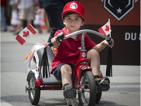 Daniel laprova, age 3, rides his bike down rue Ste-Catherine St. as he joins in the Canada day parade in Montreal, on Friday, July 1, 2016.