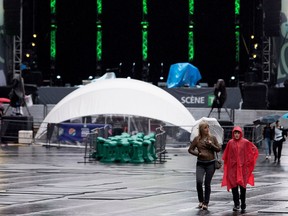 Patricia Cloudier and her son Zachery Cloudier-Davis cross an empty Place des festivals as rain falls on the Montreal International Jazz Festival in Montreal on Thursday June 29, 2017.