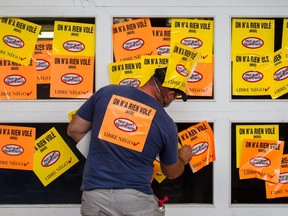 A protester supporting the firefighter's union places stickers on the garage door entrance to Montreal city hall in protest against the proposed Bill 3, a pension reform bill, in Montreal on Monday, August 18, 2014.