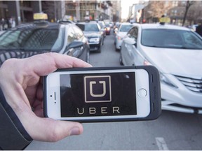 The Uber logo is seen in front of protesting taxi drivers at the Montreal courthouse on Feb. 2, 2016.