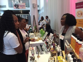 Volunteers Shanon Mathé and Séphora Bure get help from Sophia Murphy at her Roots to Curls booth during Montreal's Natural Hair Congress.