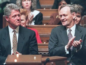 US President Bill Clinton (L) is applauded by Canadian Prime Minister Jean Chretien (R) after the Canadian leader welcomed him Feb. 23, 1995, at a joint meeting of the Canadian Parliament in the chamber of the House of Commons.