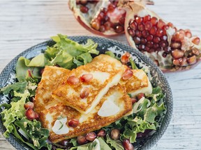 Halloumi cheese is fried and served over salad greens with a trimming of pomegranate seeds.