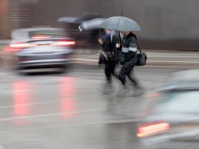 Pedestrians run across Rue de la Cathedrale St. during a rainfall in Montreal April 6, 2017.