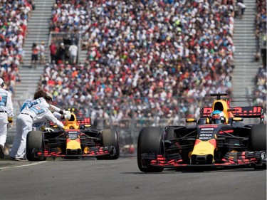 Red Bull Racing's Daniel Ricciardo passes his teammate Max Verstappen's car as pit marshals remove his car from the track during the Canadian Formula 1 Grand Prix at Circuit Gilles Villeneuve in Montreal on Sunday, June 11, 2017.