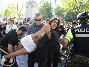 A FEMEN protester is hauled away by security and police on June 7, 2017, as she demonstrates against sexual exploitation at a Grand Prix event in Dorchester Square in Montreal.