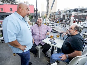 Steve Siozios, owner of Stogies Cigar Lounge and president of the Crescent Street Merchants' Association, speaks with customers Emile Tawil, right, and Alexandre Sarnouk on the terrasse at his bar on Crescent St.