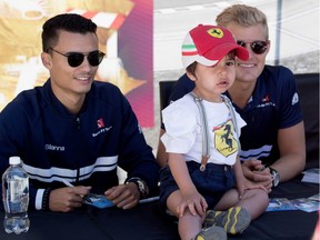 A 2-year-old boy poses for a picture with Sauber's Pascal Wehrlein, left, and Marcus Ericsson at Circuit Gilles Villeneuve in Montreal on Thursday June 8, 2017.