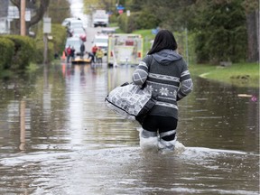 MONTREAL, QUE.: MAY 7, 2017-- With makeshift boots made from plastic and tape, Annick Sauve gives up on the idea of saving her home from rising flood waters and slowly makes her way towards Laval Firemen in Montreal on Sunday May 7, 2017. Sauve said she was forced to put her house up for sale after her partner left, she could not keep up with the mortgage payments alone and she expected to lose everything after water rose high enough to cover the main floor on her Laval West area home. (Allen McInnis / MONTREAL GAZETTE) ORG XMIT: 58xxx