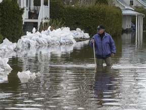 Andre Roussin checks on the water level surrounding the home of his brother  on St-Jean-Baptiste St. in Oka on Tuesday, May 9, 2017.