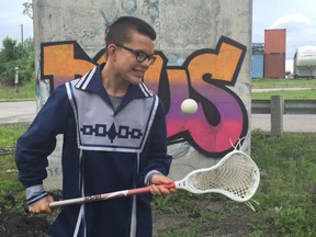 Mohawk youth poses with his lacrosse stick hours after graduating from elementary school on the Kahnawake territory.