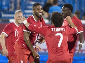 Canada's Anthony Jackson-Hamel celebrates his goal against Curacao with teammates Russell Teibert and Alphonso Davies, right, during second half of a friendly match at Saputo Stadium on Tuesday.