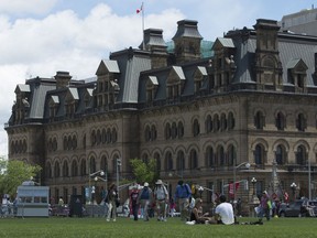 People relax on the front lawn of the Parliament buildings near Langevin Block in Ottawa, Wednesday June 21, 2017. The federal government is renaming the Langevin Block building, which sits across from Parliament Hill, out of respect for Indigenous Peoples.