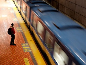 An STM passenger waits as an original metro train pulls in at the Lionel-Groulx métro station.