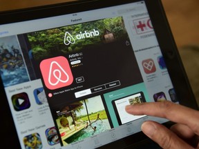 This April 2016 file photo shows a woman browsing the site of U.S. home- sharing company Airbnb.