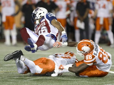Montreal Alouettes defensive back Tyree Hollins is upended by British Columbia Lions Nick Moore and Shaquille Johnson after intercepting a pass during second half of Canadian Football League game in Montreal Thursday July 6, 2017.