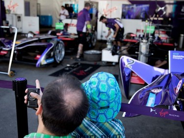 A race fan explains the action in the pits to his young son as the Virgin racing team prepares their cars during the open house for the Formula E in Montreal on Friday, July 28, 2017.