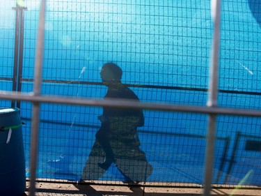 A man is silhouetted against the screening on one of several layers of fencing surrounding the Formula E race track in Montreal on Friday July 28, 2017.