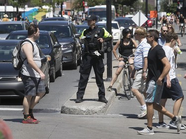 A Montreal police officer stands on corner of De Maisonneuve Blvd. and St-Denis St. to direct traffic during the qualifying round of the Formula E on Saturday July 29, 2017. (Pierre Obendrauf / MONTREAL GAZETTE)