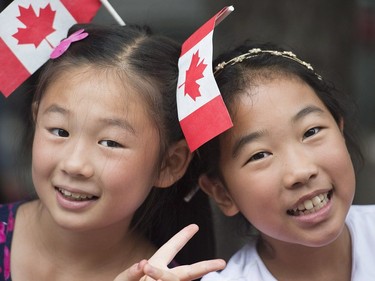 Two girls smile as they watch the annual Canada Day parade in Montreal, Saturday, July 1, 2017.