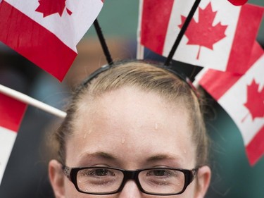 A woman wears small flags on her head as she watches the annual Canada Day parade in Montreal, Saturday, July 1, 2017.